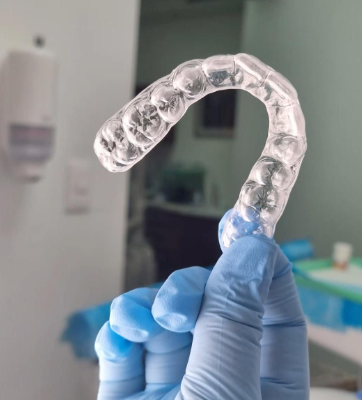 Alinhador invisível transparente sendo segurado com luva